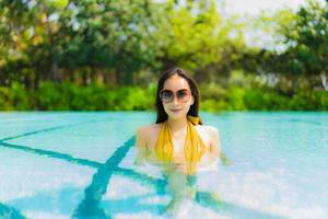 porträtt vacker ung asiatisk kvinna leende glad avkoppling och fritid i poolen foto
