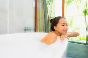 stående ung vacker asiatisk kvinna ta ett bad i badkaret foto