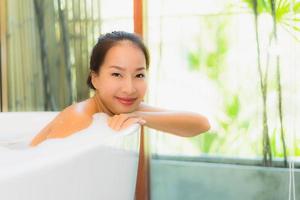 stående ung vacker asiatisk kvinna ta ett bad i badkaret foto