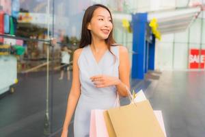 porträtt vacker ung asiatisk kvinna glad och leende med shopping väska från varuhuset foto