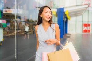 porträtt vacker ung asiatisk kvinna glad och leende med shopping väska från varuhuset foto