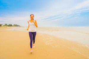 porträtt vacker ung sport asiatisk kvinna övning genom att springa och jogga på den utomhus natur stranden och havet foto