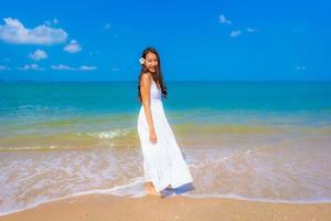 porträtt vacker ung asiatisk kvinna lyckligt leende fritid på stranden havet och havet foto