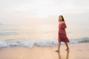 porträtt vacker ung asiatisk kvinna lyckligt leende fritid på stranden havet och havet foto