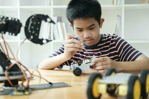 asiatisk tonåring håller på med robot projekt i vetenskap klassrum. teknologi av robotik programmering och stam utbildning begrepp. foto