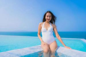 porträtt vacker ung asiatisk kvinna lyckligt leende koppla av i poolen för resor semester foto
