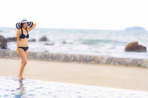 porträtt vacker ung asiatisk kvinna slitage bikini runt poolen i hotellort nästan havet ocean beach foto