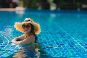 porträtt vacker ung asiatisk kvinna fritid koppla av leende och glad runt poolen i hotellort foto