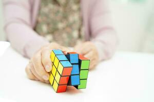 Bangkok, thailand - Maj 15, 2022 asiatisk äldre kvinna spelar rubik kub spel till öva hjärna Träning för hjälp demens förebyggande och alzheimers sjukdom. foto