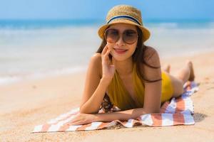 porträtt vacker ung asiatisk kvinna leende glad på stranden och havet foto