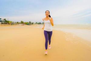 porträtt vacker ung sport asiatisk kvinna övning genom att springa och jogga på den utomhus natur stranden och havet foto