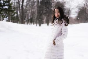 vacker ung asiatisk kvinna som ler glad för att resa i snö vintersäsongen foto