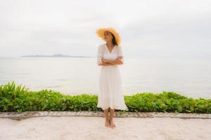 porträtt vacker asiatisk kvinna slitage hatt med leende glad fritid på stranden och havet i semester semester foto