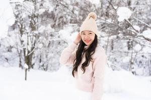 stående ung vacker asiatisk kvinna leende lycklig resa och njut av med snö vintersäsongen foto