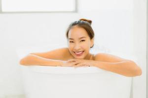 porträtt vacker ung asiatisk kvinna ta ett badkar i badrummet foto