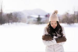 vacker ung asiatisk kvinna som ler glad för att resa i snö vintersäsongen foto