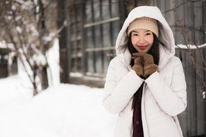 vacker ung asiatisk kvinna som ler glad för att resa i snö vintersäsongen foto