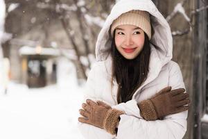 vacker ung asiatisk kvinna som ler glad för att resa i snö vintersäsongen foto