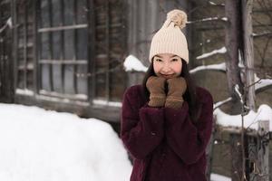 vacker ung asiatisk kvinna som ler glad för att resa i snö vintersäsongen foto