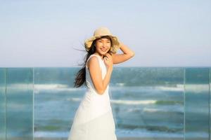 porträtt vacker ung asiatisk kvinna glad och le på stranden havet och havet foto