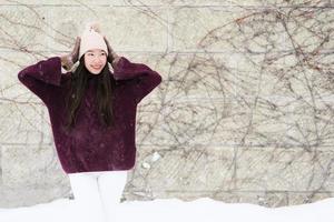vacker ung asiatisk kvinna som ler glad för att resa i snö vintersäsongen foto