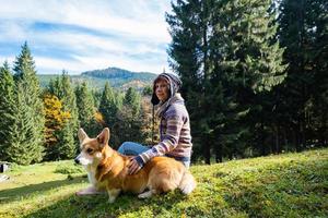 ung kvinna resenär med corgi hund i bergen foto