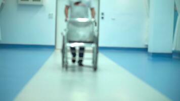 suddig scen video vinkel se av sjukhus personal, rullstol den där patient Sammanträde på Det. foto