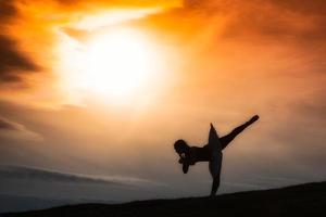 ballerina siluett, dansar ensam i naturen i bergen vid solnedgången foto