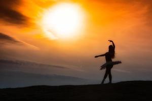 ballerina siluett, dansar ensam i naturen i bergen vid solnedgången foto