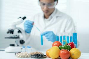 forskare kolla upp kemisk mat rester i laboratorium. kontrollera experter inspektera kvalitet av frukter, grönsaker. labb, faror, rohs, hitta förbjuden ämnen, förorena, mikroskop, mikrobiolog foto