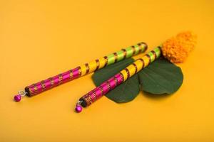 indisk festival dussehra och navratri, visar gyllene blad bauhinia racemosa och ringblomma blommor med dandiya pinnar. foto