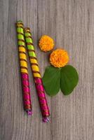 indisk festival dussehra och navratri, visar gyllene blad bauhinia racemosa och ringblomma blommor med dandiya pinnar på en trä bakgrund foto
