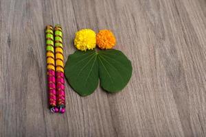 indisk festival dussehra och navratri, visar gyllene blad bauhinia racemosa och ringblomma blommor med dandiya pinnar på en trä bakgrund foto