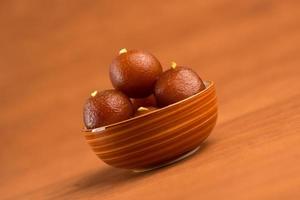 gulab jamun i skål på träbakgrund. indisk efterrätt eller söt maträtt. foto