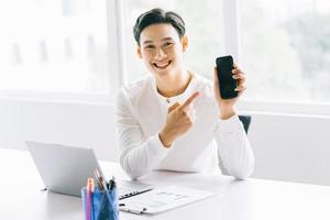 asiatisk affärsman pekade på telefonen. asiatisk affärsman arbetar på sitt kontor foto