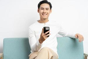 asiatisk affärsman som sitter på soffan och använder telefonen foto