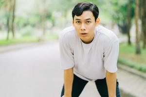 asiatisk man som vilar efter jogging i park foto