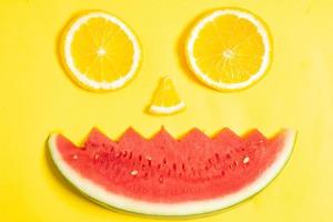 apelsinskivor och vattenmelonbitar ordnade i form av ett mänskligt ansikte