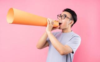 asiatisk man som håller pappershögtalare på rosa bakgrund foto