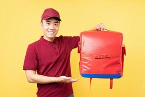 asiatisk leveransman som bär en röd uniform som poserar på gul bakgrund