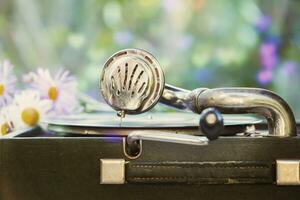 årgång skott av en retro grammofon med en vinyl spela in och en romantisk suddig bukett av blommor. foto