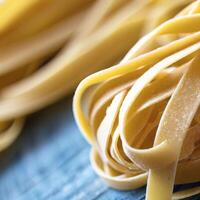 stänga upp av en rå torr italiensk pasta fettuccine på blå trä- tabell. ai generativ foto