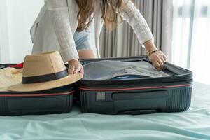 kvinna förpackning resväska på säng för en ny resa förpackning lista för resa planera framställning semester bok nu reser transport foto