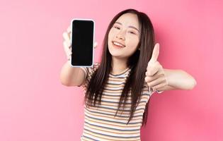 ung asiatisk kvinna som använder smartphonen på rosa bakgrund foto