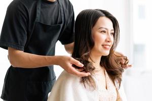 asiatisk kvinna med lyckligt uttryck gör frisör på salong foto