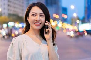 ung asiatisk kvinna som ringer när hon går på gatan på natten