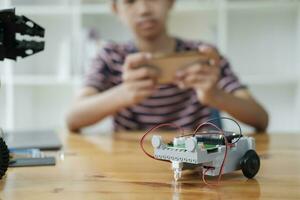 asiatisk tonåring håller på med robot projekt i vetenskap klassrum. teknologi av robotik programmering och stam utbildning begrepp. foto
