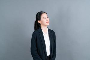 glad asiatisk kvinna med lyckligt ansikte i kontorskläder på grå bakgrund