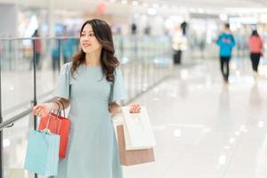 stående av ung flicka som håller shoppingpåsen som går i köpcentrum