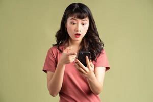den asiatiska kvinnan höll telefonen och gjorde ett förvånat ansikte foto